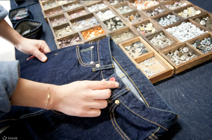Selecting buttons and rivets from wooden trays for custom jeans