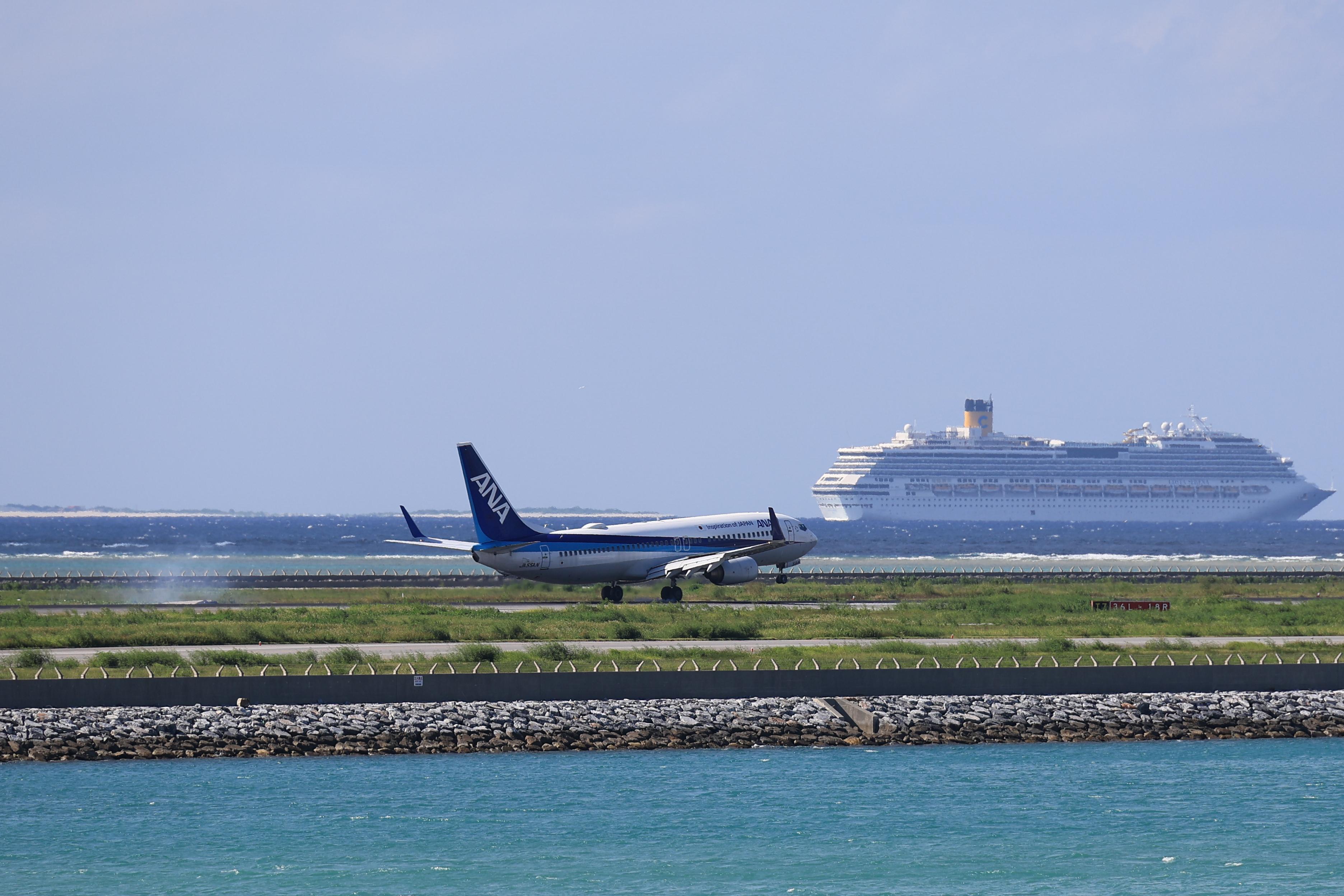 ANA plane landing with cruise ship in background