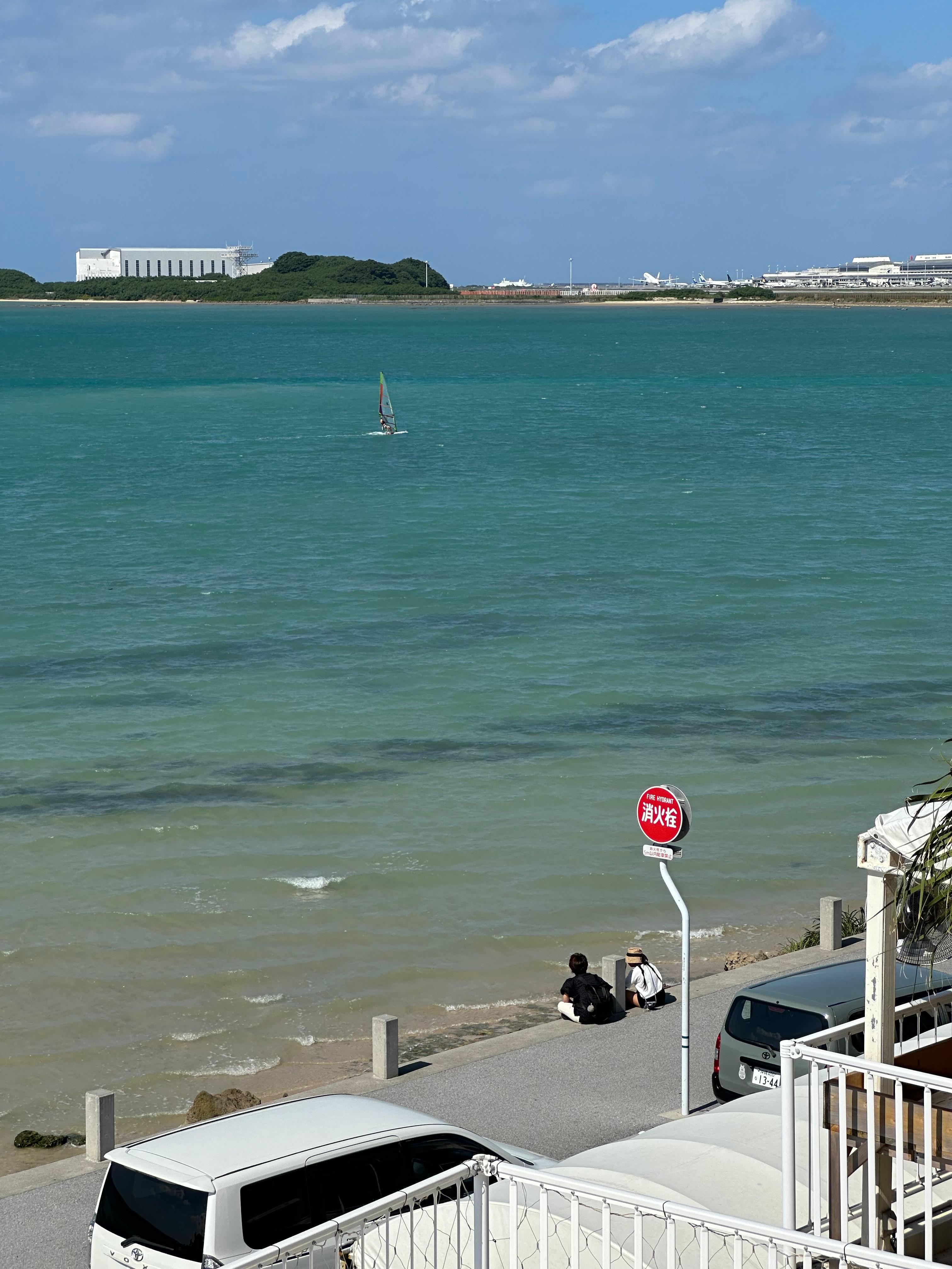 Couple sitting by the sea watching a windsurfer